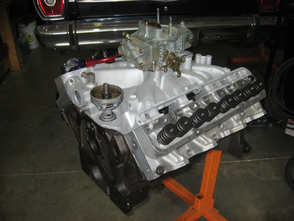 V8 short block on orange engine stand with aluminum intake, Holley carburetor and exposed valve springs