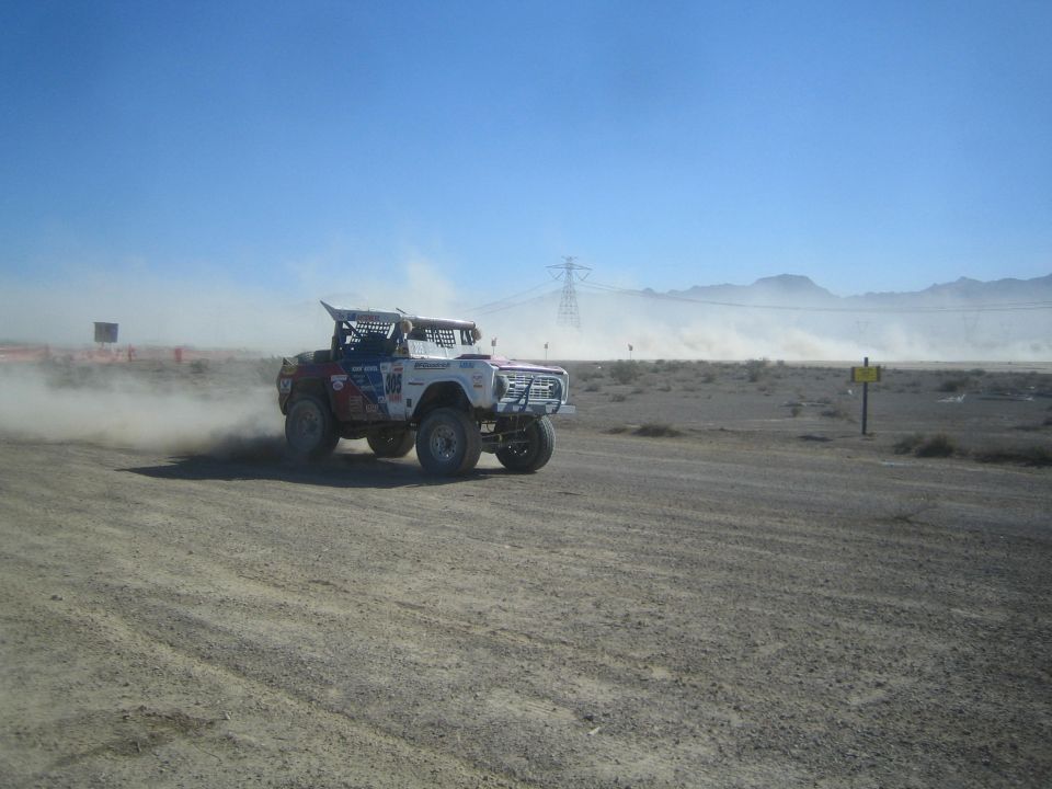 Open-bodied race truck cornering on a desert dirt course