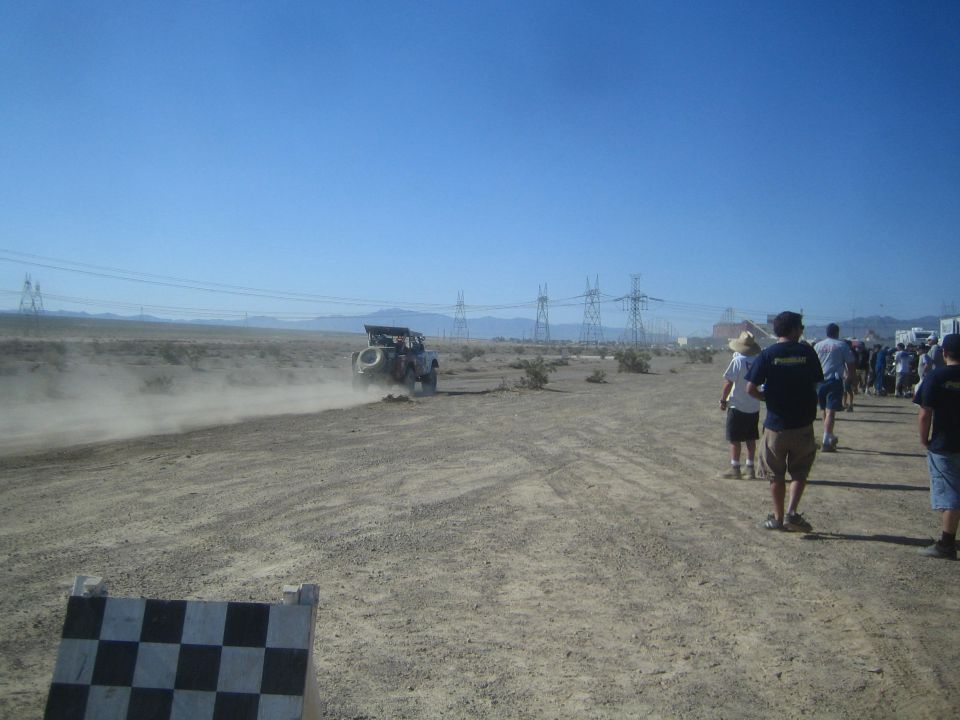 Spectators walking along a desert course as a race truck passes