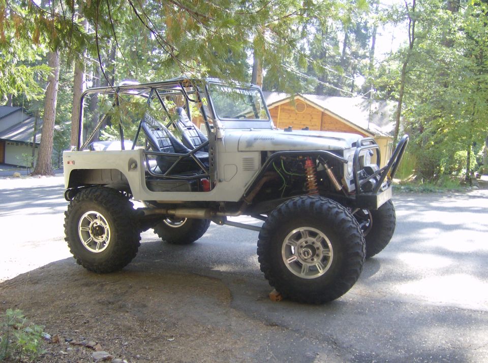 Gray off-road vehicle with roll cage and large tires, parked outdoors