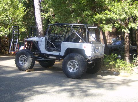1986 Ford Bronco - Custom off-road SUV with extensive modifications, parked in a wooded area. A second vehicle is partially visible.
