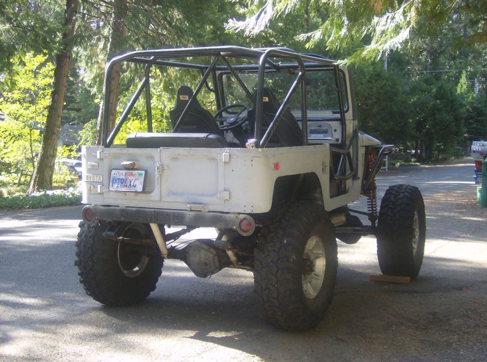 Toyota Land Cruiser FJ40 with roll cage, lifted suspension, and large off-road tires. Rear view