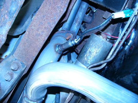 1996 Ford Bronco - Close-up view of the exhaust system, including an oxygen sensor and a portion of the starter motor.
