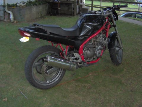 1993 Yamaha Seca II - A motorcycle sits on a grassy lawn with a fence and some structures in the background.