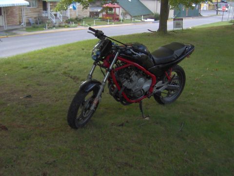 1993 Yamaha Seca II - A black motorcycle with a red frame is parked on a grassy area next to a road.