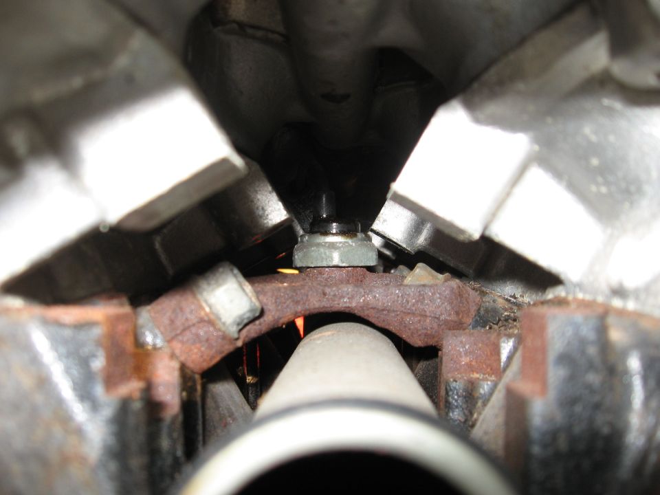 Close-up of engine component with rusty bracket and bolt