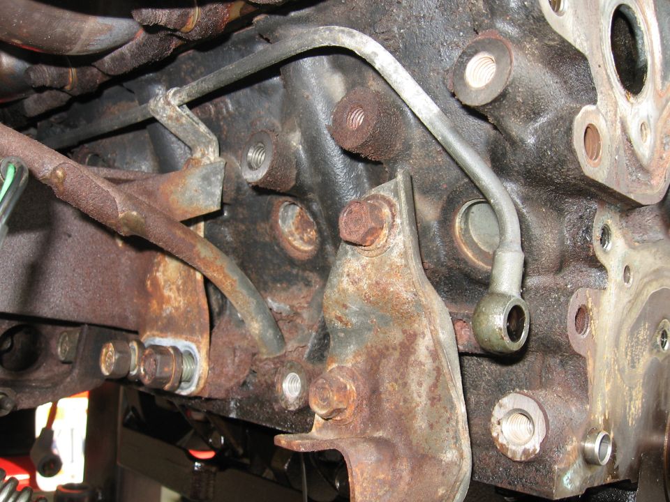 Close-up of a rusty engine block with metal fuel lines attached