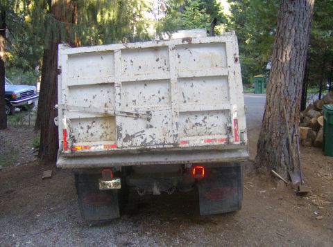 1986 Ford Bronco - Rear view of a dump truck parked outdoors, with another vehicle partially visible to the left.