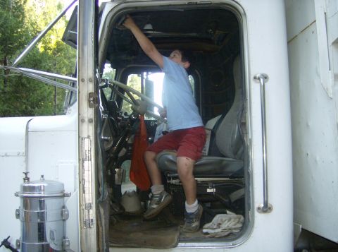 1986 Ford Bronco - A boy is inside the cab of a large truck, reaching up towards the ceiling.