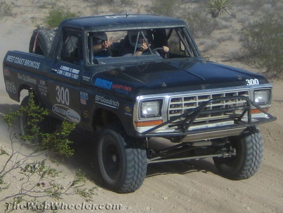 Blue vintage Ford off-road race truck number 300 driving on desert sand