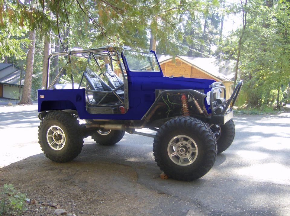 Blue custom off-road vehicle with roll cage and large tires parked outside a house