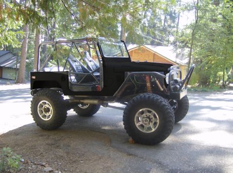 1989 Ford Bronco - This heavily modified off-road vehicle features a prominent roll cage and oversized tires, suggesting it is built for terrain.