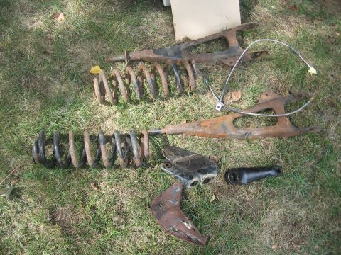 1996 Ford Bronco - Several rusty vehicle suspension components are scattered on a grassy lawn.