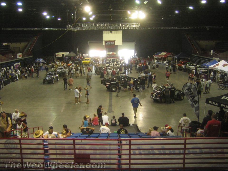 Indoor arena floor with off-road vehicles and spectators in seating