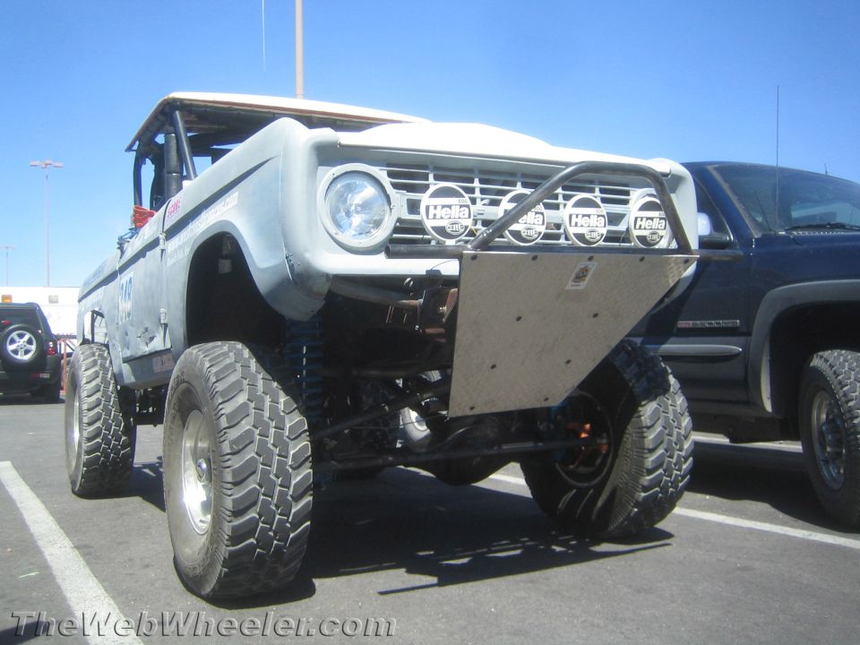 Front three-quarter of a white early Ford Bronco off-road rig in a lot