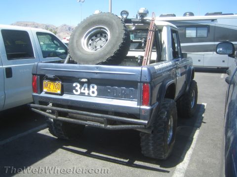 1990 Ford Bronco - Rear three-quarter view of a dark blue lifted early Ford Bronco with tube bumper, bed-mounted spare tire and the number 348 on the tailgate.