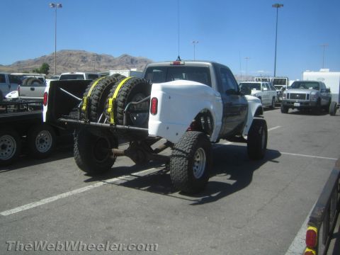 1990 Ford Bronco - Rear view of a white fiberglass-bodied Ford prerunner truck with twin rear-mounted spare tires, parked at an outdoor event.