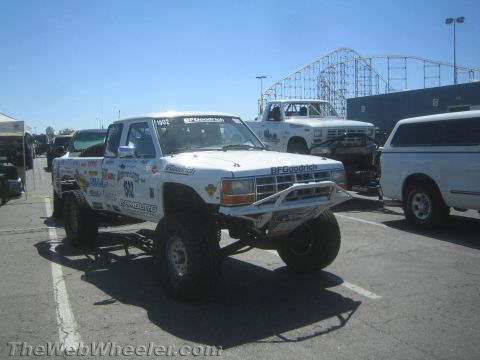 1990 Ford Bronco - Front three-quarter view of a white off-road race truck wearing number 502 and BFGoodrich sponsor graphics in a sunny paved lot.