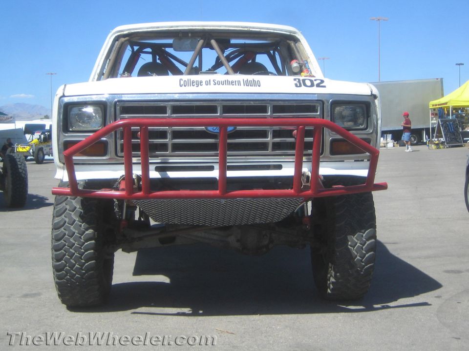 Front view of white Ford race truck 302 with red tube bumper and roll cage