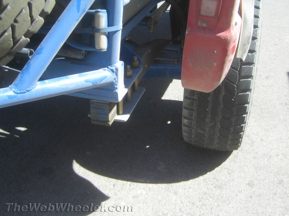 Rear suspension detail with blue tube frame, leaf springs and red fender of off-road truck