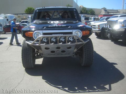 1990 Ford Bronco - Front view of a black Toyota FJ Cruiser built as an off-road race truck, with a row of KC lights, tube bumper and skid plate.
