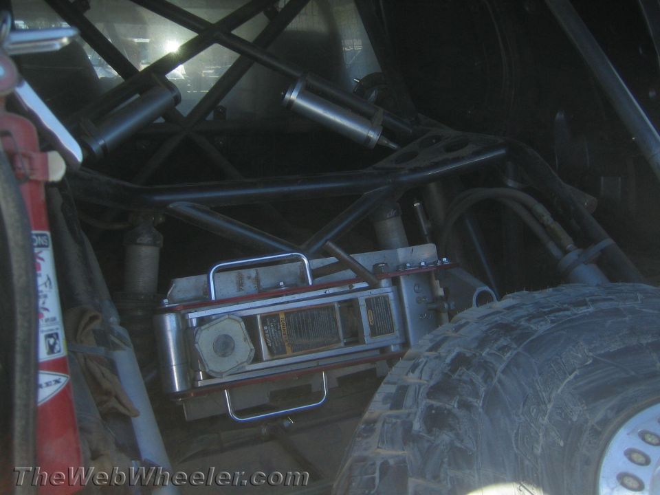 Dark rear cage view with mounted fire extinguisher, shocks and off-road tire