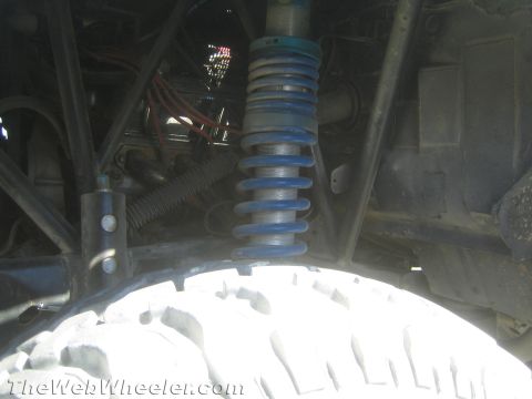 1990 Ford Bronco - close-up shows a blue coilover spring shock mounted above a large off-road tire beneath a vehicle.