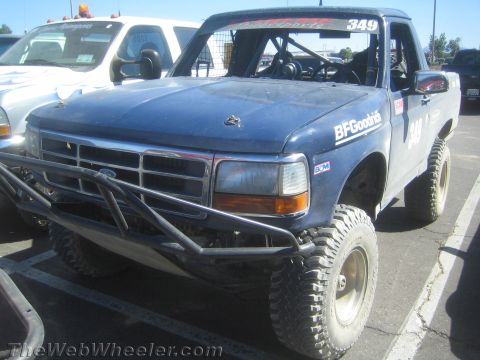 1990 Ford Bronco - blue lifted Ford prerunner numbered 349 with a tubular front bumper and amber lights sits angled in a paved lot.