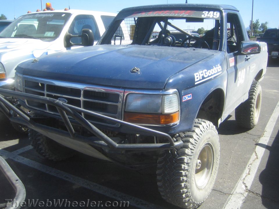 Front three-quarter of blue lifted Ford prerunner truck No. 349 with tube bumper in lot