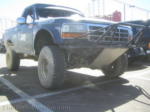 1990 Ford Bronco - blue lifted Ford off-road race truck numbered 349 shows its tubular front bumper, skid plate and large mud tires.