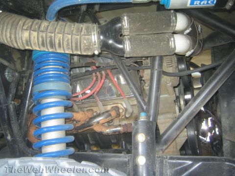 1990 Ford Bronco - engine bay of an off-road truck shows a blue coilover spring, exhaust headers, red spark plug wires and an intake hose.