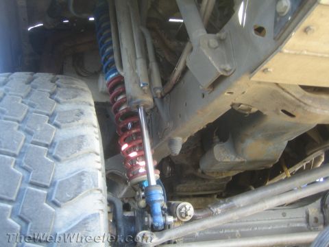 1990 Ford Bronco - close-up shows a red coilover spring over a shock with steering and suspension components under a lifted truck.