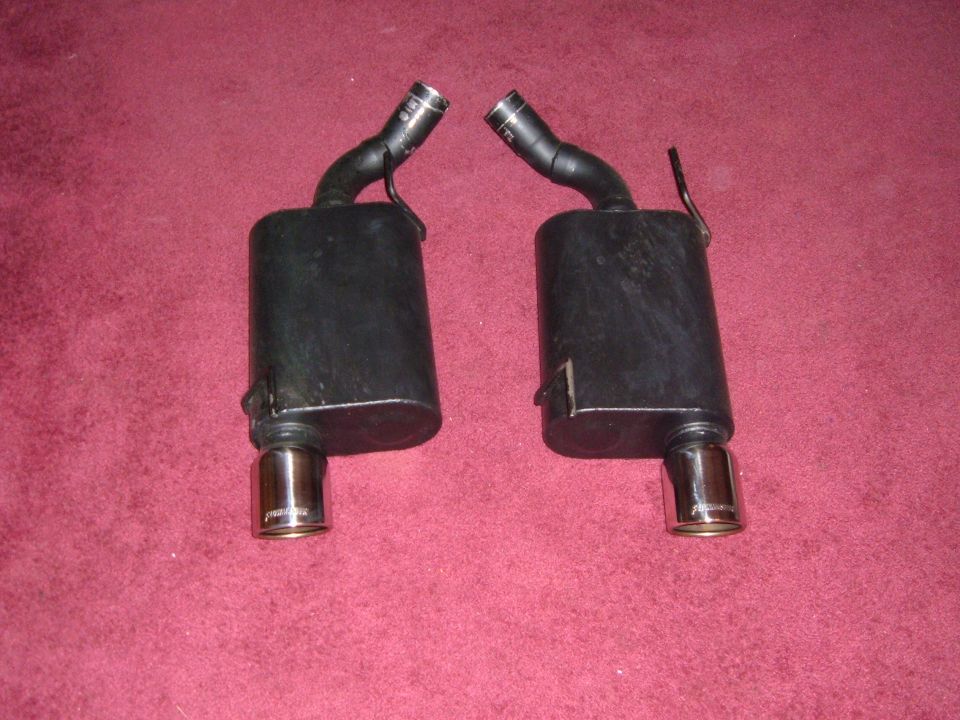 Pair of black mufflers with chrome tips, one with a bent pipe