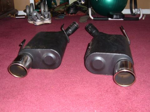 2007 Ford Mustang - Pair of exhaust mufflers shown on a carpeted floor with gym equipment in the background.