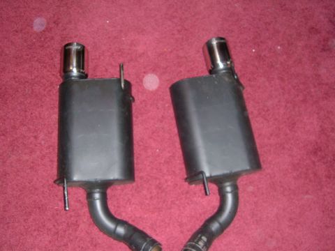 2007 Ford Mustang - Two exhaust mufflers are shown against a red carpet background. The website 'supermotors.net' is visible in the lower right corner.