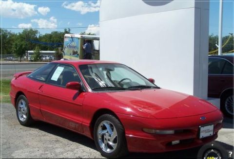 1996 Ford Probe - A red 1996 Ford Probe GT is parked outside on a sunny day, showing off its sporty design and aftermarket wheels.