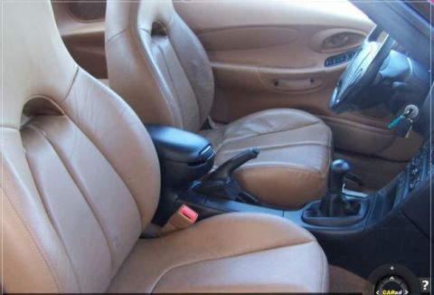 1996 Ford Probe - The interior of a car shows tan leather seats, a center console with a gear shifter, and the steering wheel.
