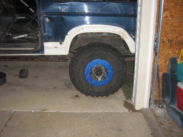 Blue truck rear wheel with white fender flare, mud tire and blue 8-lug steel wheel