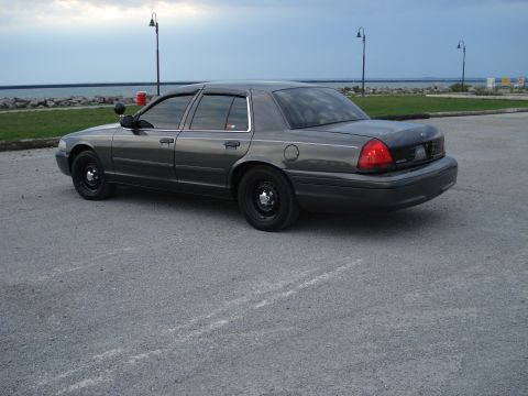 2000 Ford Crown Victoria - Dark gray Ford Crown Victoria parked near the water under a cloudy sky.