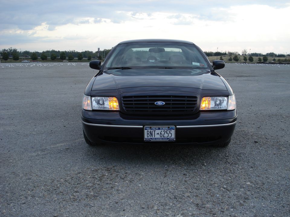 Front view of dark blue Ford Crown Victoria with New York plate in gravel lot