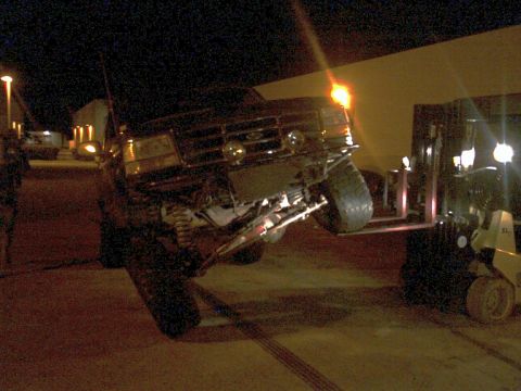 1996 Ford Bronco - Forklift lifting a 1996 Ford Bronco at night.