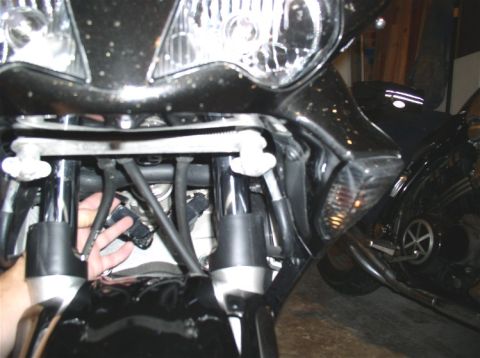 1990 Ford Bronco - Close-up view of a motorcycle's front assembly, showing wiring and suspension components, with a second motorcycle in the background.