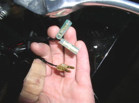 1990 Ford Bronco - Close-up of electrical connectors, likely for a motorcycle, with a bandaged finger in view.