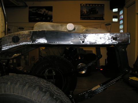 1986 Toyota Hilux - Close-up of a truck's frame and fuel tank, with part of a leaf spring visible. Text on the spring reads "TOY-RI...".