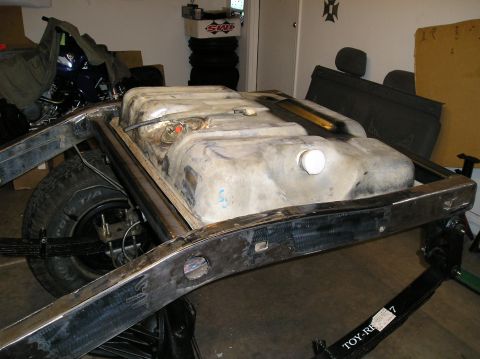 1986 Toyota Hilux - A large fuel tank is mounted to a vehicle's frame, with a rear leaf spring assembly visible below.