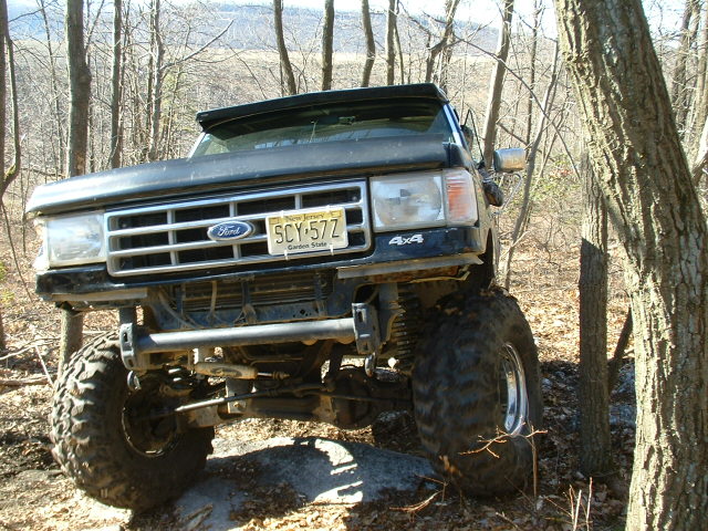 Black Ford F-Series truck with large tires on a rocky trail, front view