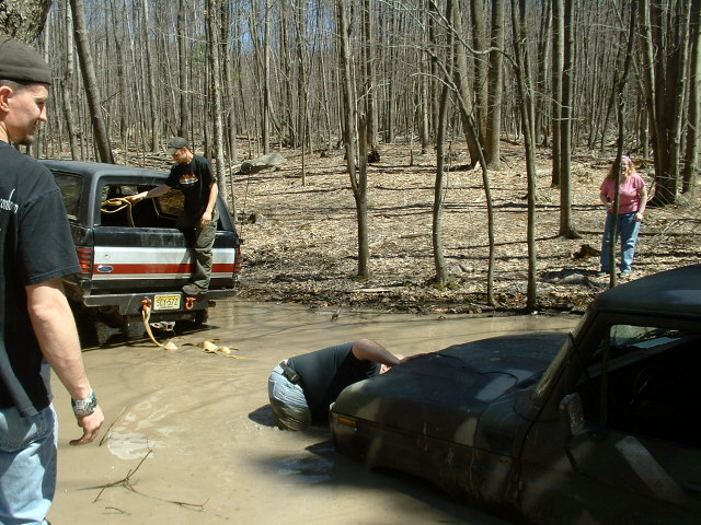 Off-road vehicles stuck in mud with people around