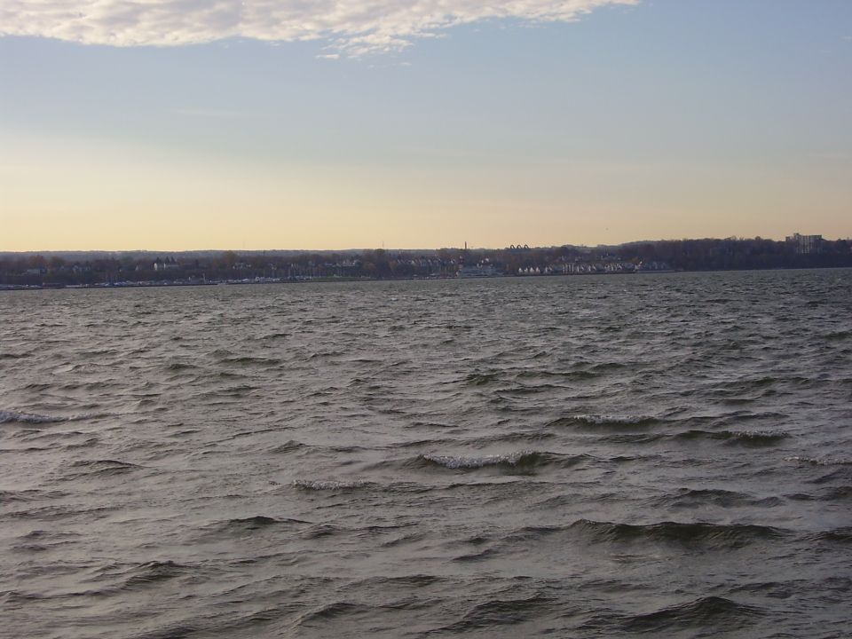 Water with a distant shoreline under a cloudy sky. Supermotors logo visible