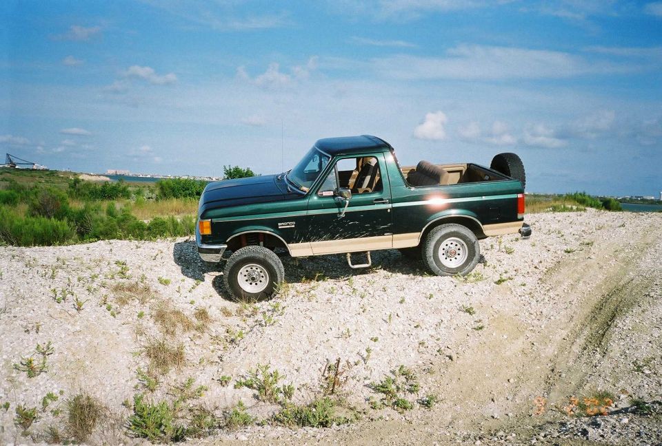 Green Ford F-Series truck with tan lower body trim parked on a dirt road