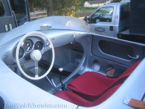 1990 Ford Bronco - cockpit of a silver spyder roadster shows a white steering wheel, round gauges and a red bucket seat.